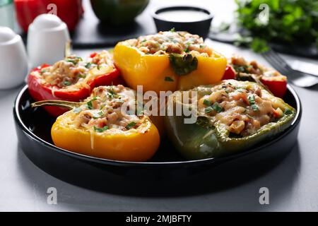 Leckere gefüllte Paprika, serviert auf einem grauen Tisch Stockfoto