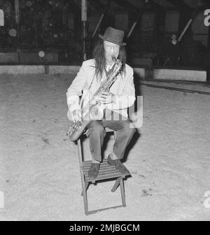 Niederländische Geschichte: Künstler treten im Circus Boltini auf. Laut der Originalunterschrift für dieses Foto ist dieser Mann der berühmte holländische Oboist Jaap Statijn, der im Alter von 70 Jahren ein Saxophon spielt und als musikalischer Clown verkleidet ist; Datum: 4. Juli 1962 Stockfoto