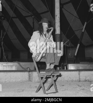 Niederländische Geschichte: Künstler treten im Circus Boltini auf. Laut der Originalunterschrift für dieses Foto ist dieser Mann der berühmte holländische Oboist Jaap Statijn, der im Alter von 70 Jahren ein Saxophon spielt und als musikalischer Clown verkleidet ist; Datum: 4. Juli 1962 Stockfoto