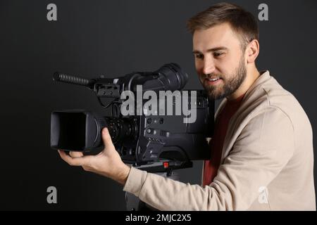 Bediener mit professioneller Videokamera auf schwarzem Hintergrund Stockfoto