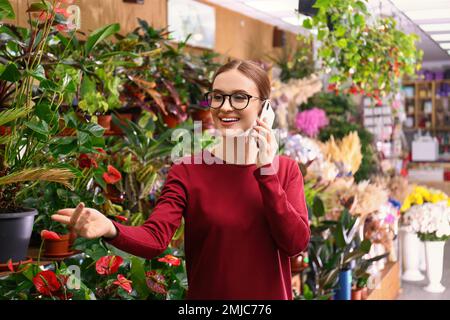 Weibliche Geschäftsinhaberin, die im Blumenladen telefoniert Stockfoto