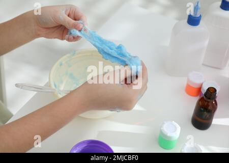 Kleines Mädchen, das Heimwerker-Schleim-Spielzeug am Tisch macht, Nahaufnahme Stockfoto