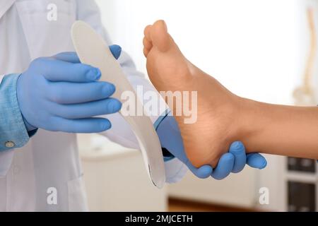 Die Einlegesohle des männlichen Orthopäden am Fuss des Patienten in der Klinik, Nahaufnahme Stockfoto
