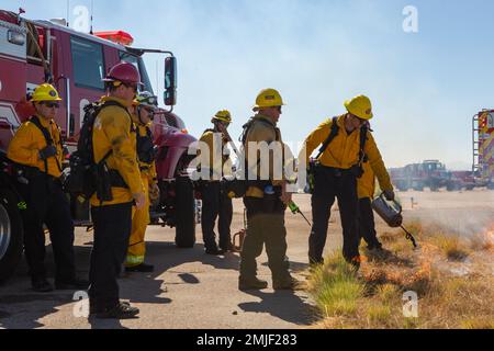 Feuerwehrleute von der Marine Corps Air Station Miramar Fire Department 61 und San Diego Fire Rescue beginnen am 27. August 2022 im MCAS Miramar, San Diego, Kalifornien, ein vorgeschriebenes Brandereignis. Die vorgeschriebene Verbrennung wurde als vorbeugende Maßnahme durchgeführt, um Unterbürsten oder entzündliche Substanzen zu beseitigen, die während der MCAS Miramar Air Show 2022 Feuer ausbreiten könnten. Stockfoto