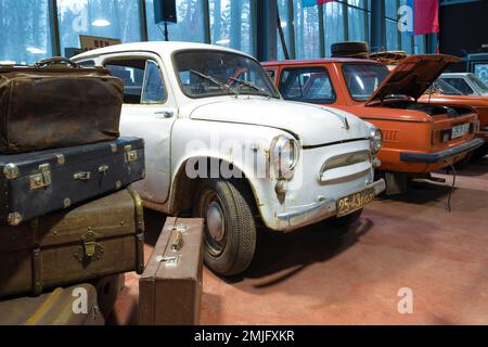 ZELENOGORSK, RUSSLAND - 27. JANUAR 2021: Der alte Zaporozhets ZAZ-965 schaut hinter einem Haufen alter Koffer heraus. Museum der Retro-Autos „Pferdestärken“ Stockfoto
