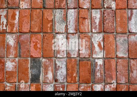 Nahaufnahme einer verwitterten roten Backsteinmauer. Stockfoto