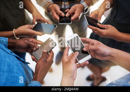 Im intelligenten Zeitalter auf dem Laufenden bleiben. Eine Gruppe von Menschen, die ihre Smartphones synchron verwenden. Stockfoto