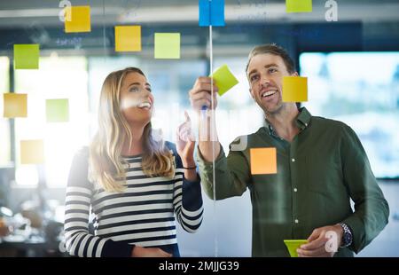 Eine großartige Idee zu entwickeln. Kollegen, die bei der Arbeit ein Brainstorming mit Haftnotizen durchführen. Stockfoto