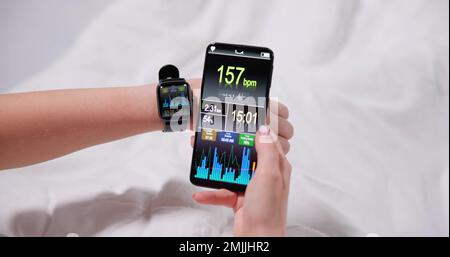 Woman's Hand zeigt Herzfrequenz auf Smart Watch und Handy Stockfoto