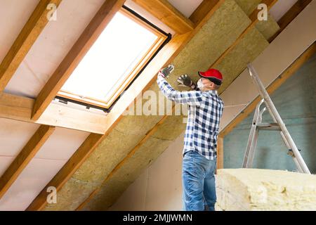 Installation von Dämmstoffen im Dachboden für die Hausrenovierung. Ökologisches Heimkonzept. Stockfoto