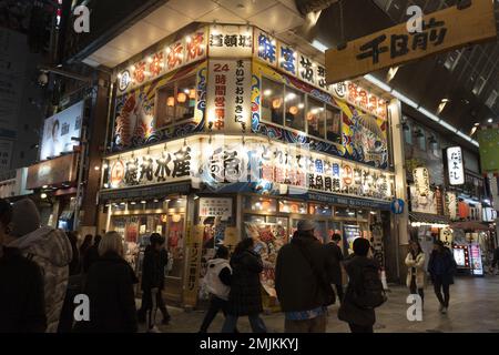 Nachtschau durch die überfüllte Sennichimae Doguyasuji Shopping Street in Osaka, Japan Stockfoto