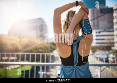 Das beste Projekt, an dem du je gearbeitet hast, bist du. Rückansicht einer sportlichen jungen Frau, die sich vor dem Laufen streckt. Stockfoto