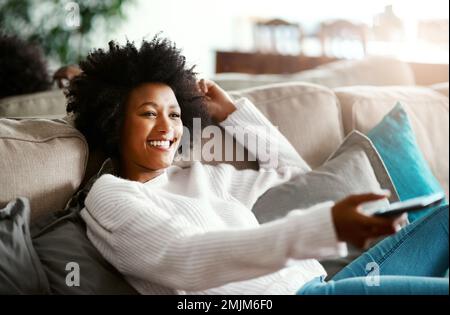 Manche Tage waren nur dafür bestimmt. Eine junge Frau, die sich zu Hause auf dem Sofa entspannt und fernsieht. Stockfoto
