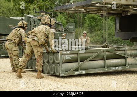 USA Soldaten, die der Arctic Battery, dem 1. Bataillon, der 6. Artillerie, der 41. Artillerie-Brigade zugeteilt wurden, verwenden das integrierte Windensystem, um Raketensysteme in das M270. Multiple Launch Rocket System (M270 MLRS) zu laden, um eine Live-Feuerdemonstration während des „Molly Pitcher Day“ am Trainingsgelände Grafenwoehr, 31. August 2022, vorzubereiten. Stockfoto