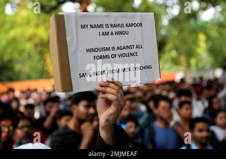 An Indian man holds a placard condemning recent mob lynching of Muslim