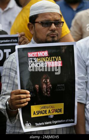 An Indian man holds a placard condemning recent mob lynching of Muslim