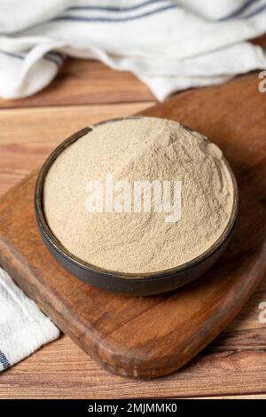 Gewürzpulver mit weißem Pfeffer. Gemahlene weiße Pfefferkörner in einer Schüssel auf Holzhintergrund. Trockengewürz-Konzept. Schließen Stockfoto