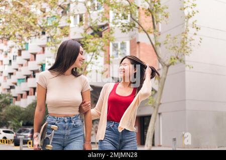 Frauen, die Arm in Arm durch die Stadt schlendern Stockfoto
