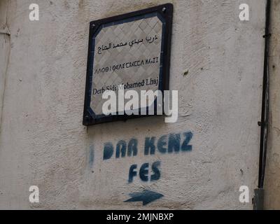 Ein kleines Straßenschild dreisprachiges arabisches französisch und Berber in der mittelalterlichen Medina von Fez Fes (Altstadt). Marokko. Stockfoto