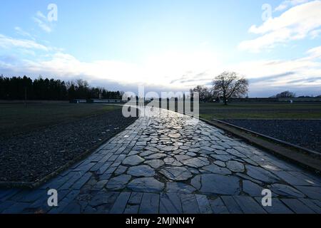 Oranienburg, Deutschland. 27. Januar 2023. Ein Pfad führt über das Gelände des Sachsenhausen-Gedenkmals und -Museums. Während einer gemeinsamen Veranstaltung des Brandenburger Landesparlaments und der Gedenkfeier wurde zum ersten Mal, anstatt einen Kranz zu legen, eine Tonband-Kunstaktion mit der Frage durchgeführt: "Warum erinnern Sie sich heute?" Kredit: Soeren Stache/dpa/Alamy Live News Stockfoto