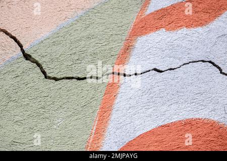 Großer Wicklungsriss an der alten mehrfarbigen Putzwand. Speicherplatz kopieren. Selektiver Fokus. Stockfoto