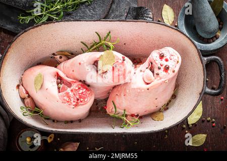 Zubereitung für gebratenes Schweinefleisch in einer ovenenfesten Schale. Roher Schinken mit Gewürzen und Knoblauch. Stockfoto