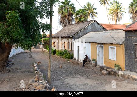 Einheimischer Mann, der vor einem alten traditionellen Haus in der ältesten Siedlung auf Cabo verde sitzt, Cidade Velha Dorf auf der Insel Santiago in Cabo verde Stockfoto