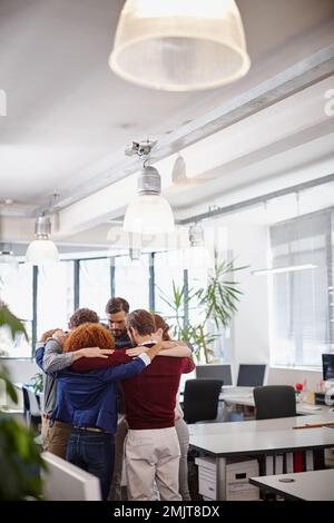 Sich selbst auf die nächste Herausforderung vorzubereiten. Ein Team von Geschäftsleuten, das sich mitten im Büro zusammensetzt. Stockfoto