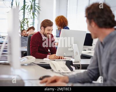 Arbeiten hart oder arbeiten kaum. Geschäftskollegen, die in ihrem modernen Büro an Computern arbeiten. Stockfoto
