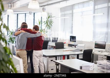 Bereiten Sie sich auf einen weiteren Arbeitstag vor. Ein Team von Geschäftsleuten, das sich mitten im Büro zusammensetzt. Stockfoto