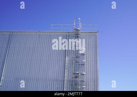 Leiter zum Dach eines hohen Industriegebäudes mit blauem Himmel Stockfoto