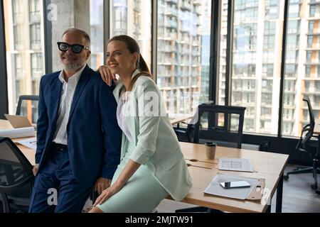 Zwei freundliche Kollegen in Geschäftskleidung posieren gerne im Büro Stockfoto