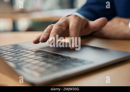 Männlicher Büroangestellter, der während der Arbeit an einem Laptop ein Touchpad verwendet Stockfoto