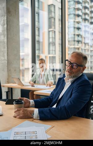 Stilvoller Mann mittleren Alters, der eine Kaffeepause im Büro macht Stockfoto