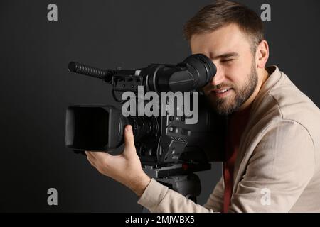 Bediener mit professioneller Videokamera auf schwarzem Hintergrund Stockfoto