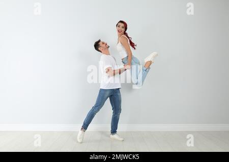 Ein hübsches junges Paar tanzt an der hellen Wand Stockfoto