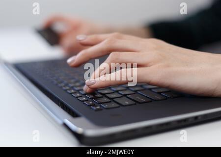 Frau, die online einkauft. Weibliche Person kauft im Webshop mit Kreditkarte und Laptop Stockfoto