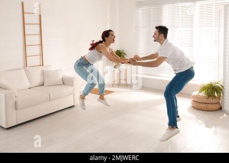 Wunderschönes junges Paar, das im Wohnzimmer tanzt Stockfoto