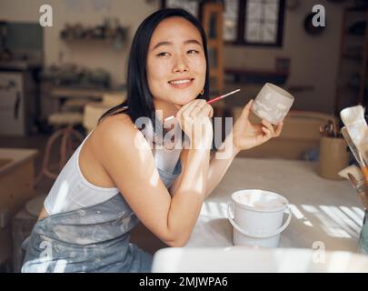 Frau, Töpfer oder Denken an Ideen für Produktdesign, Tassenmalerei oder kreative Farben in asiatischen Töpferstudios. Lächeln, glücklich oder Lehmarbeiter Stockfoto