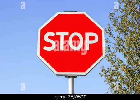 Hellrot und weiß Stoppschild am blauen Himmel. Stockfoto