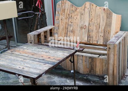 Außentisch aus recyceltem Holz aus alter Holzlagerpalette im Garten der Terrasse Stockfoto