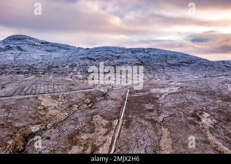 Der R251 neben dem schneebedeckten Berg Errigal, der höchste Berg in Donegal - Irland Stockfoto