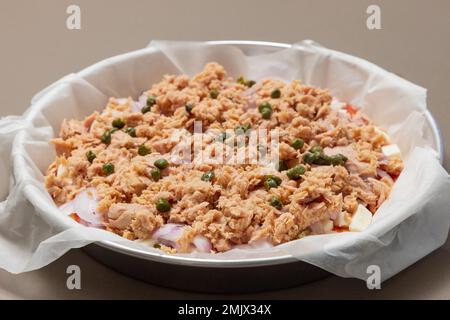 Ungekochte hausgemachte italienische Pizza mit Thunfisch, Zwiebeln und Kapern auf Backpapier (selektiver Fokus) Stockfoto