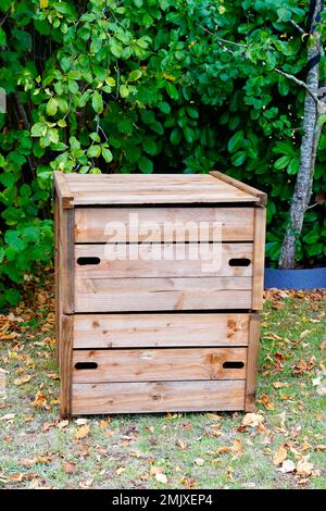 Geschlossener Kompostbehälter aus Holz für den Garten mit organischem Kompostiermaterial im Außenbereich des Hinterhauses Stockfoto