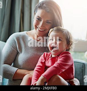 Entspannen, glücklich und lachen Sie mit Mutter und Baby auf dem Sofa, um sich zu verbinden, eine schöne Zeit zu verbringen und die Entwicklung des Kindes zu fördern. Wachstum, Unterstützung und lustig mit mom und Stockfoto
