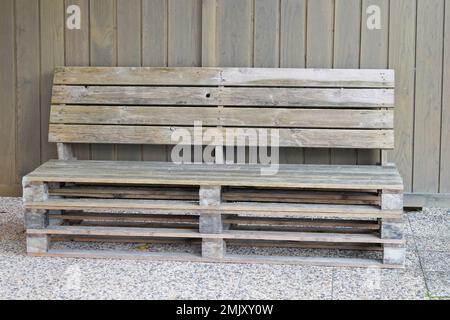 Außenbank aus alter Holzlagerpalette im Hausgarten Stockfoto