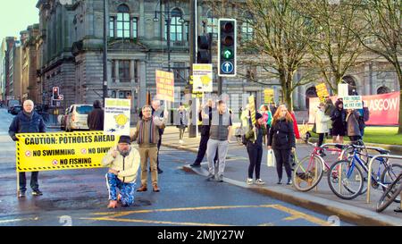 Glasgow, Schottland, Vereinigtes Königreich 28. Januar 2023. Schlagloch-Protest vor dem hauptquartier des rates auf dem george Square sah, wie eine große Menge Plakate Demonstranten mit einem von der Menge finanzierten Banner winkten und die Zustimmung von vorbeifahrenden Autofahrern erhielten, als sie am Straßenrand mit einem großen Schlagloch posierten. Credit Gerard Ferry/Alamy Live News Stockfoto