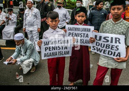 Bogor, Indonesien. 27. Januar 2023. Indonesische Schulkinder halten während eines Protests gegen Schwedisch-Dänisch ein Plakat, um die jüngste Entweihung des heiligen islamischen Buches Koran durch einen rechtsextremen Politiker Rasmus Paludan in Bogor, West-Java, Indonesien, am 27. Januar 2023 anzuprangern. Die globale islamische Gemeinschaft verurteilte Islamfeindlichkeit, nachdem der schwedisch-dänische rechtsextreme Politiker Rasmus Paludan bei einer Kundgebung in Stockholm am 21. Januar eine Kopie des Korans verbrannte. (Foto: ANDI M RIDWAN/INA PHOTO AGENCY/SIPA USA) Guthaben: SIPA USA/Alamy Live News Stockfoto