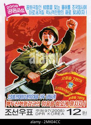 2008 Nordkorea-Stempel. Nordkoreanischer Zeitungsartikel. KPA Soldat fliegt mit Gewehr vor Stockfoto