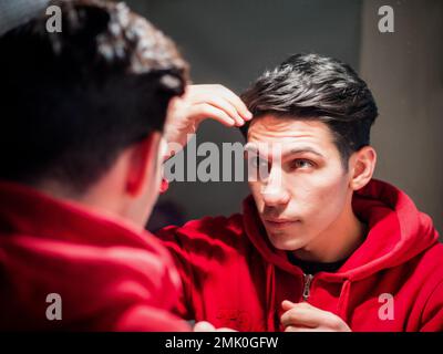 Ein gutaussehender Mann, der sein Gesicht im Spiegel sieht Stockfoto